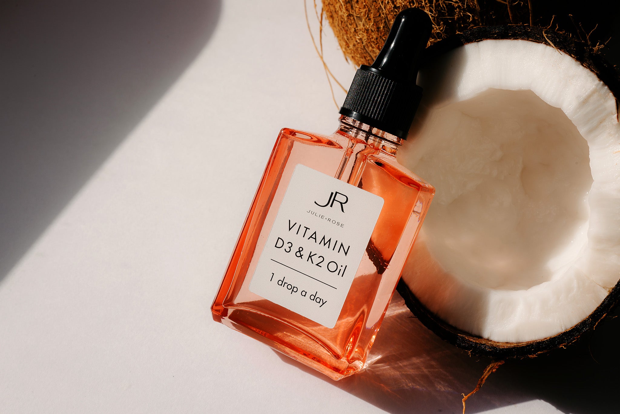 JULIE & ROSE - Vitamin D3+K2 Öl 30 ml - Flasche schräg an halbierter Kokosnuss